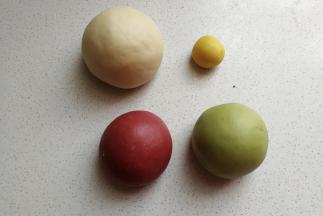 接下来把均等的两份分别加入抹茶粉和红曲粉，揉均匀揉成光滑的面团，15克的小面团也加入少许南瓜粉揉均匀，然后再把四份面团放入烤盘中，盖上保鲜膜进行发酵。