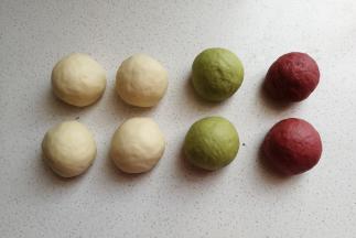 接下来把白色的面团分成均等的四份滚圆，彩色面团各分成均等的两份也滚圆，再盖上保鲜膜静置十分钟左右。