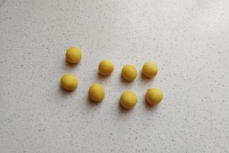 黄色的小面团分成均等的八个小剂子搓圆，然后盖上保鲜膜把它放入冰箱冷藏待用。