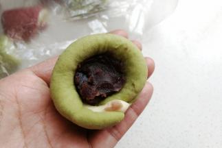 再取适量豆沙馅放入窝形中，然后收口包紧。