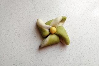 叠好后用筷子在中间按压几下，然后取出先前冷藏的黄色小面团摆上去，这样一个风车面包胚就完成了。