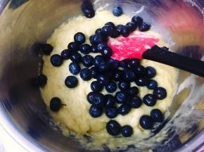 接着倒入之前过筛好的面粉混合物（步骤2），用刮刀翻拌均匀后加入洗净的三分之二的蓝莓，轻轻地拌匀。