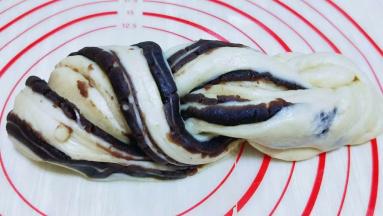 切开后拿起来一条，从正中间对折（豆沙馅表面外翻）接下来就像拧麻花那样拧好，两头收紧即可。