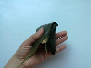 把粽叶从上面折下来盖住，成四角形。