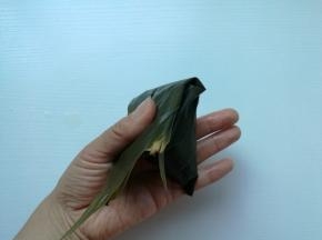 把粽叶从上面折下来盖住，成四角形。