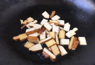 用少许油将香干两面煎一下，煎至两面稍稍有金黄色，盛出备用。