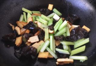 当花椒油油温6或者7成热时，放入木耳、芹菜段、香干，翻炒均匀。