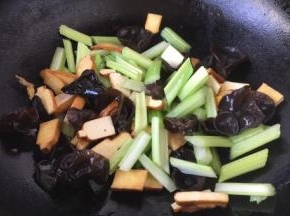 当花椒油油温6或者7成热时，放入木耳、芹菜段、香干，翻炒均匀。
