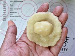 4、取一份水油皮拍扁，放入一个油酥，包起来。