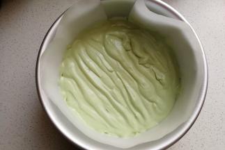 接下来先取一半的抹茶慕斯糊装入裱花袋，然后在蛋糕片上挤上一层抹茶慕斯糊，用小抹刀把表面稍微抹平，然后放入冰箱冷藏至表面凝固。