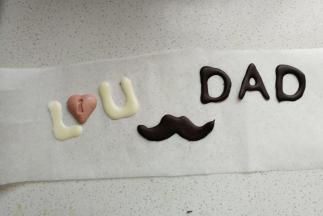 再取各种颜色的巧克力融化，在油纸上画出字母，小爱心和小胡子。