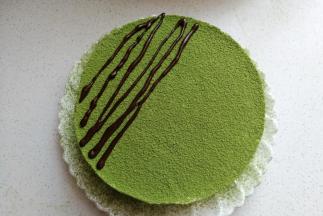 接下来再取少许巧克力放入裱花袋中隔热水融化，然后在抹茶表面拉上巧克力线条，最后再把巧克力字母和小爱心，小胡子等插上装饰即可。