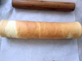 用擀面杖将蛋糕卷卷起来，卷的时候一定要卷紧，因为蛋糕外层还要卷一层虎皮层，蛋糕的表面可以不用太在意，脱皮或者用毛巾面都可以