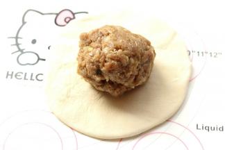 把100克调好的肉馅团成球，放入面皮里。