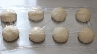 将分好的面团滚圆，盖上保鲜膜静置15分钟左右