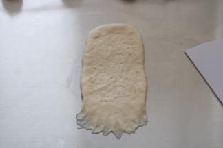 将擀好的面团翻面，用手指拉开底部的面团，做收口用。