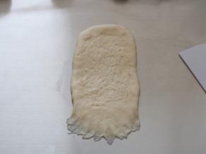 将擀好的面团翻面，用手指拉开底部的面团，做收口用。