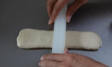 擀面杖也依照第一次擀卷手法一样，从中间向上向下擀开