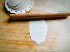 取一张饺子皮，用擀面杖擀出长舌状。