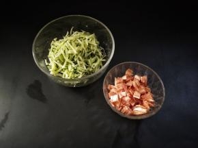 黄瓜擦丝加入少许的盐将其腌出汁水。培根切成小片，放入锅里面煸至微黄盛出备用