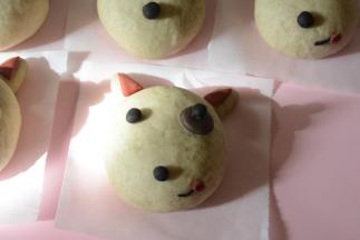 未用完的浅黑色面团再加入少许深黑可可粉揉至光滑，揉成颜色黑一些的小面团。取少量搓成5个小圆球，涂上水粘在脸部靠下的位置做鼻子。然后在揉成大小一致的小圆球10个作为眼睛，涂上水粘在眼睛的位置。剩下的红面团压出小圆片，适当拉长一下，压出一道痕，粘在鼻子边做舌头（这个步骤可以省略，如果想要汪星人俏皮一些可以加上这步骤。）