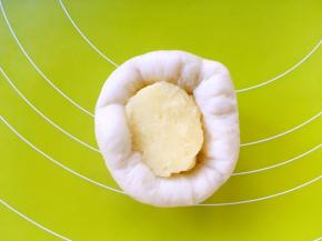 之后将面片翻个面，将光滑的一面朝下，包裹上一块卡士达酱，收好收口