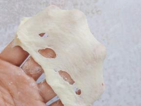 当面团揉至面筋形成粗膜的状态时，将擀碎的亚麻籽和黄油一起加入搅拌缸中