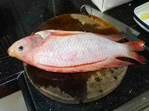 首先在鱼的脊背上划上一刀，脊背是鱼最厚的部分，切一刀可以让鱼熟得更快，也更入味。