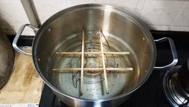把铁架架在锅中，再在铁架上用两双筷子摆出一个井字形