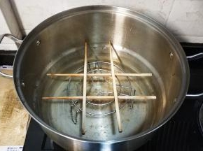 把铁架架在锅中，再在铁架上用两双筷子摆出一个井字形