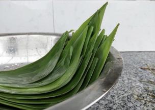 将粽叶放在清水中浸泡，用刷子刷洗干净。