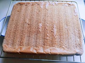 烤好的蛋糕片，戴上隔热手套取出，倒扣再烤网上，撕掉油纸，立即将蛋糕翻过来。面朝上，晾凉。