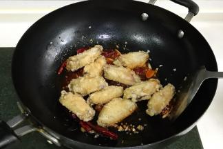 加入炸好的鸡翅，翻炒几下。