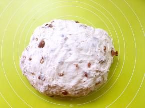 将发酵好的面团取出，放在揉面垫上按压排气