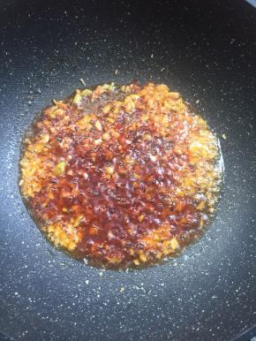 锅烧热倒入适量的油，放入蒜末和郫县豆瓣酱炒出香味儿来。