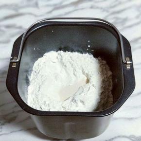 除黄油外的食材全部加入面包桶，先倒入牛奶，盐和糖对角放，草鸡蛋2个，奶粉，再加入高筋面粉，最后再面粉的顶端挖个洞，把酵母粉加入洞洞里，再用周边的面粉盖起来。