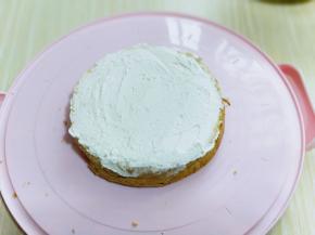 取一片蛋糕，放在器具中，抹上一层打发的奶油。