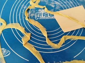 取出一块面团，中间用筷子压出一道痕迹，然后从中间往两边慢慢扯长，最后从中间的痕迹撕开，分成两根面条。