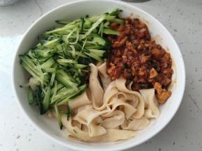 把煮好的面装入碗中，挖上一大勺炒好的酱，再来上黄瓜丝，一碗自制的拌面就完成了。