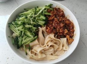 把煮好的面装入碗中，挖上一大勺炒好的酱，再来上黄瓜丝，一碗自制的拌面就完成了。