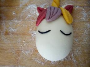 用黑色面团搓条做出独角兽的眼睛，借助牙签粘上去