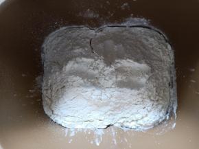 面包机先放入牛奶，对角放盐和糖，再放入高筋面粉，中间挖个洞放入酵母。启动揉面程序15分钟。