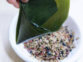 煮好的粽子剪去硬的那部分叶子梗，卷成一个锥行筒。