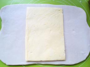 冰箱取出冷冻的黄油片，用剪刀裁开保鲜袋，将黄油片放在面片中间