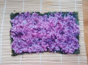 7 把拌匀的紫薯米饭均匀的铺在紫菜上，紫菜的两端也要有米饭粒。如果觉得米饭比较粘，可以用勺子沾水，有勺背来把米饭推均匀。用手来操作的话，也可以在手上抹些凉开水，或寿司醋防止黏手。