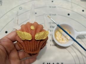 这个奥特曼的头上装饰先用巧克力再油纸上画出形状，凝固后插到玛德琳上，再涂上金粉就可以了。