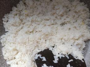 锅内放入米饭翻炒、将米饭炒散。