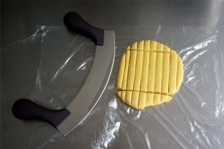 利用牛轧糖弧形切刀，将面片切成1厘米宽，8厘米长的长方条。用一般菜刀切也行，但是用这个弧形切刀切起来更方便。