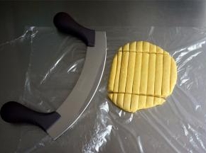 利用牛轧糖弧形切刀，将面片切成1厘米宽，8厘米长的长方条。用一般菜刀切也行，但是用这个弧形切刀切起来更方便。