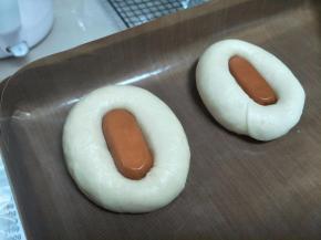 取小香肠，放置到圈圈中间，放置到烤盘上。